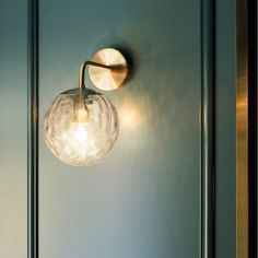 a light that is on the side of a wall next to a glass door with a metal handle