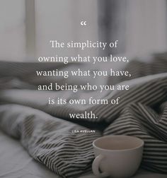 a coffee cup sitting on top of a bed next to a window with the words, the simplity of owning what you love, wanting what you have, and being who you are