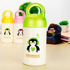 three children's water bottles with penguins on them sitting on a table next to a potted plant