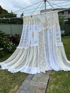 an old white lace curtain hanging on a clothes line in front of a brick walkway