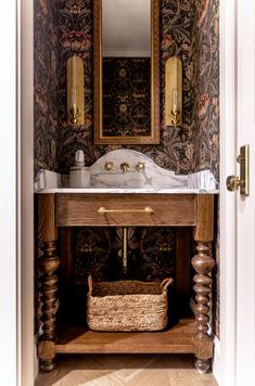 a bathroom sink sitting under a mirror next to a wooden cabinet with a basket on it