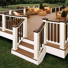 a wooden deck with chairs and tables on it next to a grassy area in the background