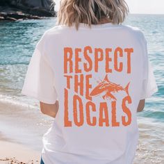 a person standing on the beach wearing a t - shirt that says respect the locals