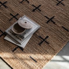 a brown rug with black crosses on it and a metal canister sitting on top