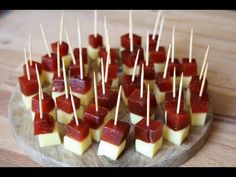 small appetizers with toothpicks are arranged on a wooden platter