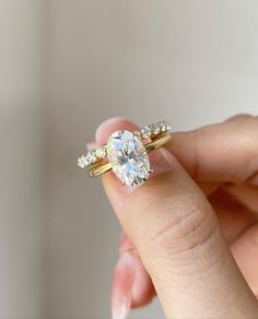 a woman's hand holding an engagement ring with two diamonds on top of it