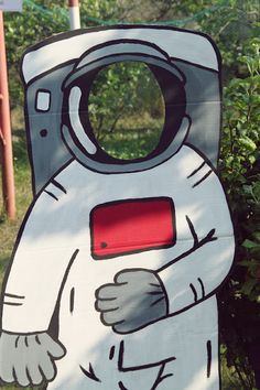 a cardboard cut out of an astronaut standing in front of some bushes and shrubbery