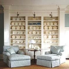 a living room filled with furniture and lots of white plates on the wall behind it