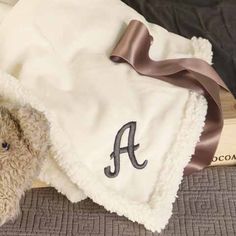 a teddy bear under a blanket with the letter a on it