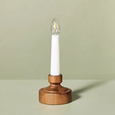 a small white candle with a wooden stand