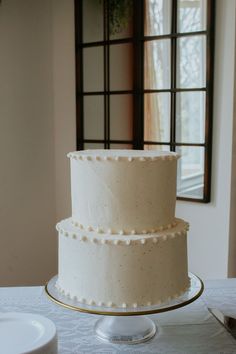 a three tiered cake sitting on top of a table next to a plate and window