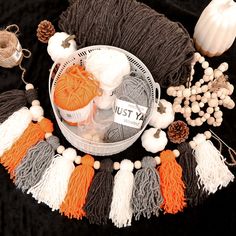 yarn, needles and balls of yarn are arranged on a black tablecloth with white pumpkins