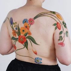 the back of a woman's body with flowers painted on her chest and shoulder