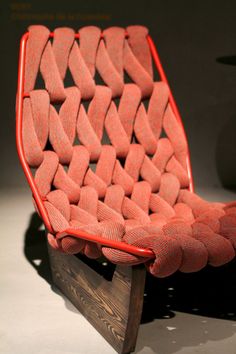 a chair made out of red fabric and wood with no cushions on the seat is shown in front of a black background