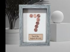 a frame with some buttons in it next to a potted plant