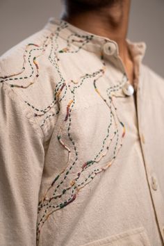 a close up of a person wearing a white shirt with colorful stitching on it