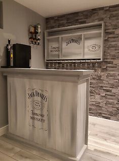 a bar with two wine bottles on the top and shelves above it in a room