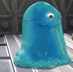 an odd looking blue object sitting on top of a metal floor next to a building