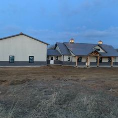 an empty field with two large buildings in the background and one building on the other side