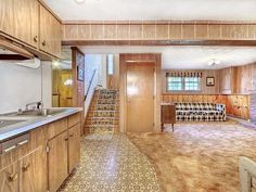 an empty kitchen and living room with stairs leading up to the second floor, as well as wood cabinets