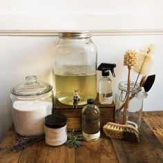 a wooden table topped with jars filled with different types of cleaning products and scrubs