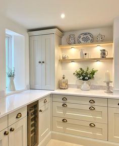 a kitchen filled with lots of white cupboards and counter top space next to a window