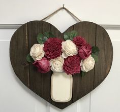 a heart shaped wooden sign with flowers on it