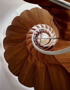 a spiral staircase made out of wood and metal with a white handrail in the center