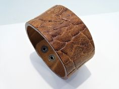 Absolutely unique Leather Cuff Bracelet, Wide Brown Wristband, Unique Statement Greek Jewelry with Embossed Pattern, Genuine leather cuff bracelet, Unique gift Simple but high quality men's bracelet made of the best Greek leather.  It is an absolutely natural product and every piece being unique.  The natural marks should not be considered faults but rather that they add to the beauty and character of the item. Every piece of leather is handmade and it has been made from high quality vegetable tanned full grain natural tooling leather. The thickness that we use is 3.5mm to 4mm and it gives the wearer a reassuring sense of strength, quality and endurance. It is an adjustable bracelet in 2 different sizes at 19cm (7.48 inches) and 21cm (8.26 inches). And the width is 37mm (1.45 inches). Impo Brown Cuff Bracelet With Waxed Finish For Gift, Brown Cuff Bracelet With Waxed Finish As Gift, Brown Waxed Finish Cuff Bracelet For Gift, Brown Waxed Finish Cuff Bracelet As Gift, Rustic Brown Cuff Bracelet As Gift, Rustic Brown Cuff Bracelet Gift, Waxed Finish Leather Cuff Bracelet As Gift, Hand-tooled Cuff Bracelets As Gift, Hand Tooled Cuff Bracelets As A Gift