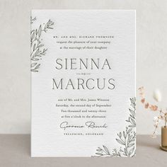 an elegant wedding card with greenery on it