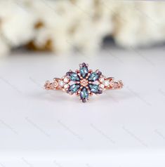 a ring with blue and white stones on it sitting on a table next to flowers