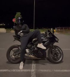 a person sitting on top of a motorcycle in the middle of a parking lot at night