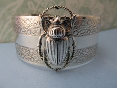 "Myelegantthings presents a gorgeous Scarab Beetles cuff.bracelet. I made these in 1970's for my jewelry line, \"Angelina Verbuni Designs\" 1 inch engraved cuff opens in back The scarab is about 1 inch. 18 K matt gold plating over brass All brass vintage findings. Chic! I have other bangles I've made also with bumble bees, panthers, butterflies and lions and lots of necklaces to match also. Available in silver or gold All USA made" Victorian Brass Silver Bracelets, Silver Brass Cuff Jewelry, Silver Brass Cuff Bracelet As Gift, Vintage Brass Cuff Jewelry, Vintage Nickel Free Cuff Jewelry, Nickel-free Vintage Cuff Jewelry, Vintage Nickel-free Cuff Jewelry, Vintage Brass Cuff Bracelet Gift, Vintage Etched Cuff Bangle