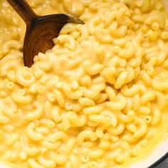 macaroni and cheese is being stirred with a wooden spoon in a large pot