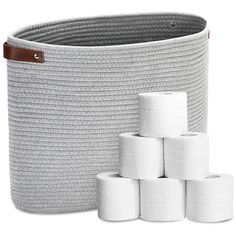 several rolls of toilet paper are stacked in a large basket next to the roll holder