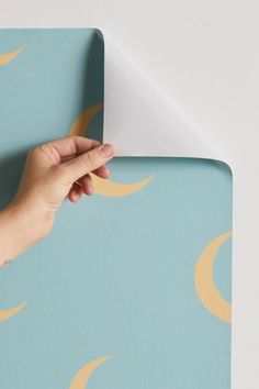 a person's hand on top of a blue and yellow wallpaper with crescents