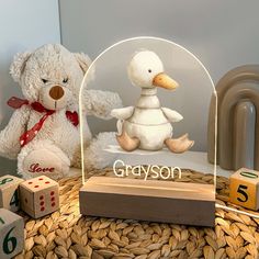 a white teddy bear sitting next to a glass globe with the word grayson on it