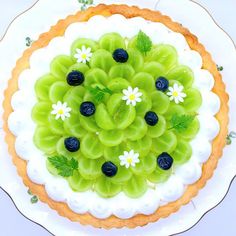 a cake decorated with grapes and flowers on a white plate, top view from above