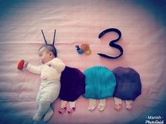 a baby laying on top of a bed next to numbers and hair clips in the shape of animals