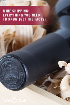 a bottle of wine sitting on top of a wooden table next to garlic and mushrooms