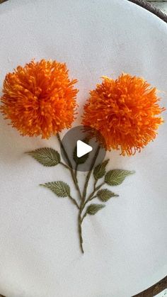 two orange pom - poms sitting on top of a piece of white fabric