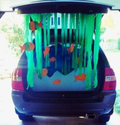 the back end of a car decorated with green streamers, fish and seaweed