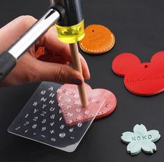 a person is making mickey mouse magnets on a black table with markers and glue