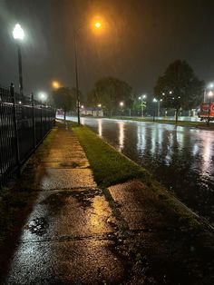 the street is flooded with water and lights shine brightly in the dark sky above it