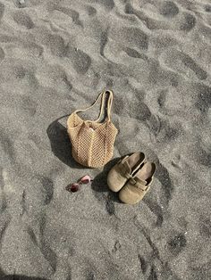 a pair of shoes and a purse on the sand