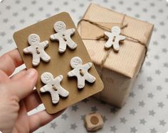 a person holding a small box with some little gingers on it next to a present