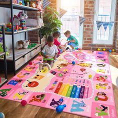 two children playing on a play mat in a room full of toys and bookshelves