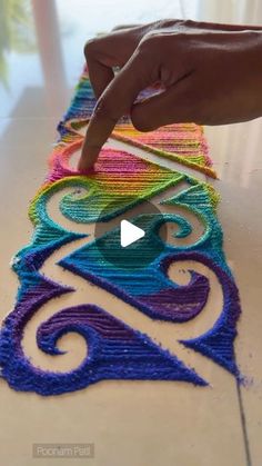 someone is using yarn to make a rainbow design on the floor with their fingers and thumbnails