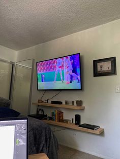 a flat screen tv sitting on top of a wooden shelf next to a laptop computer