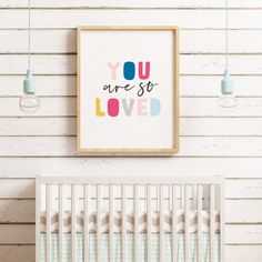 a baby's room with a white crib and wooden wall hanging above it